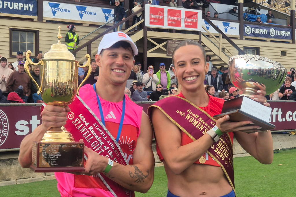 John Evans, winner of the 2025 Stawell Gift, and Bree Rizzo, winner of the 2025 Women's Gift, proudly lift their trophies aloft.